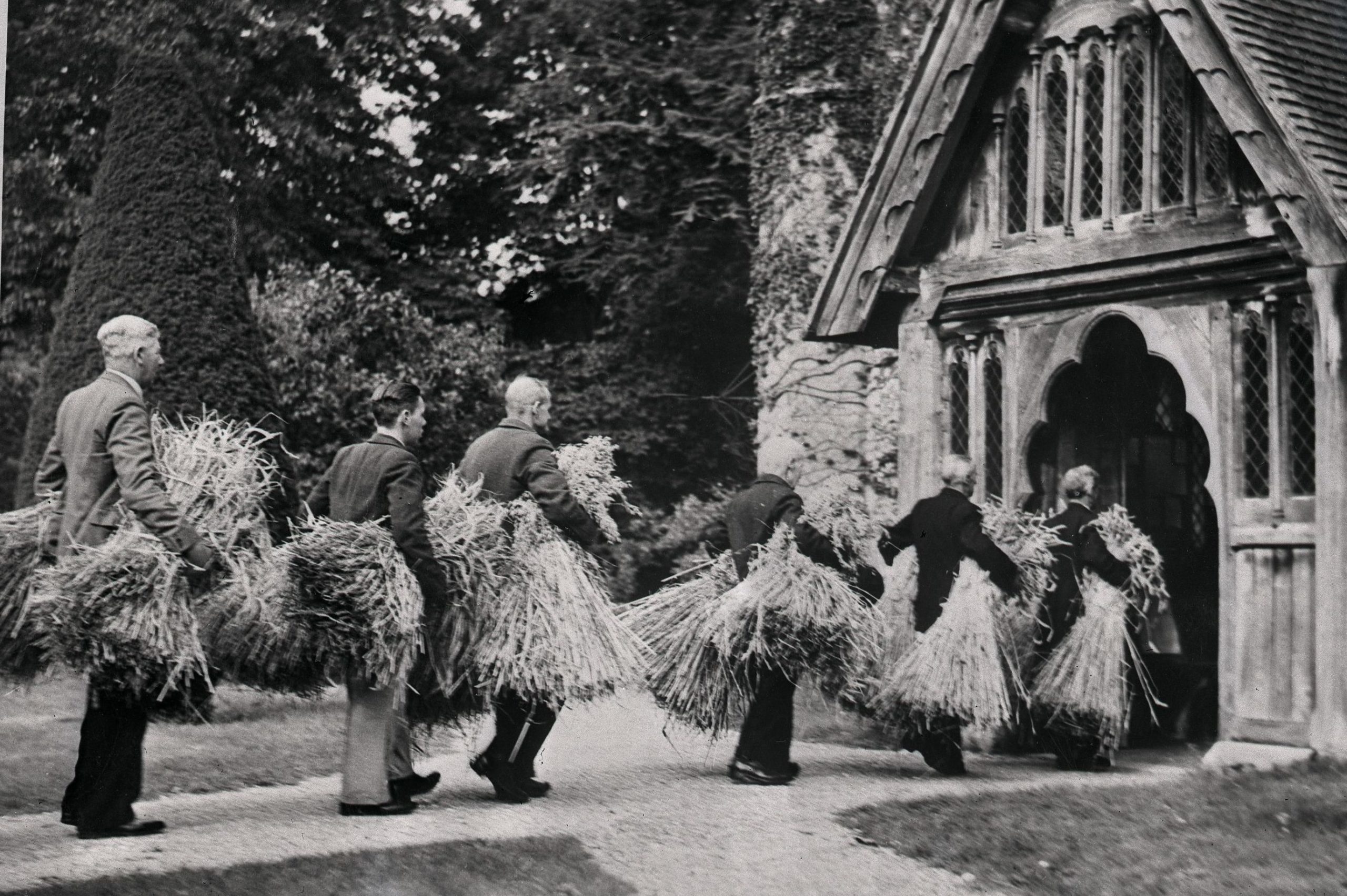 Photo of men carrying straw into a church
